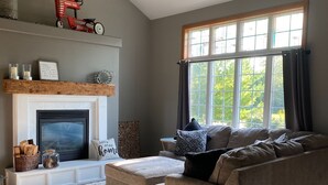 Una sala de estar con chimenea, un sofá, una alfombra y una ventana con cortinas.