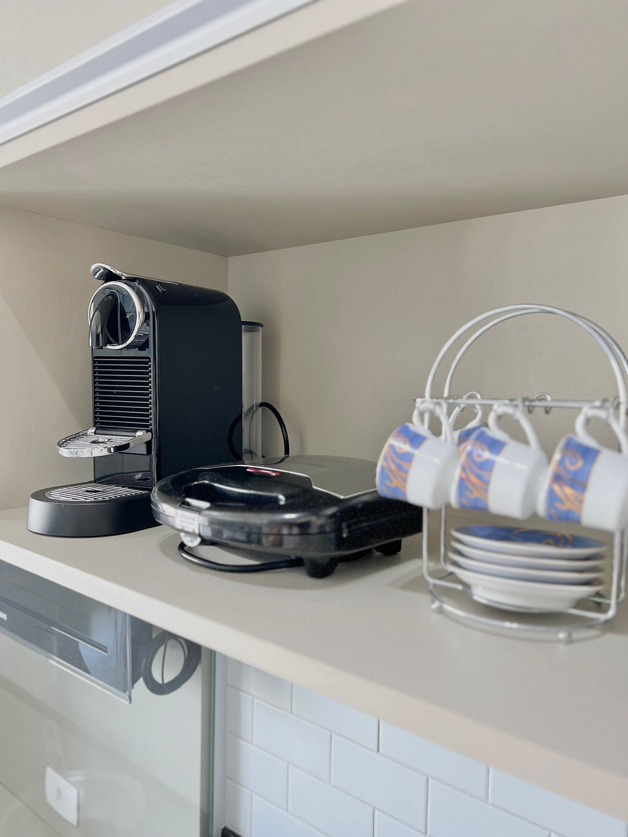 A kitchen counter with a coffee machine, a plate rack, and a cup holder.