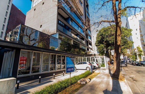 A modern building with a sign for 'STUDIOS' and a tree in the foreground.