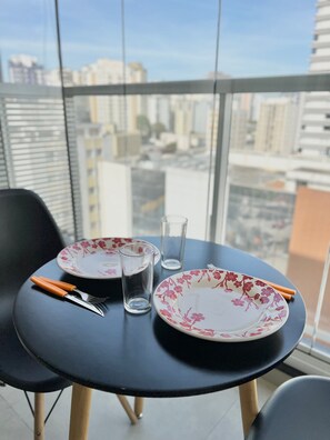 A round table with two floral plates, a fork, a knife, and a glass. - VN Quatá (São Paulo)