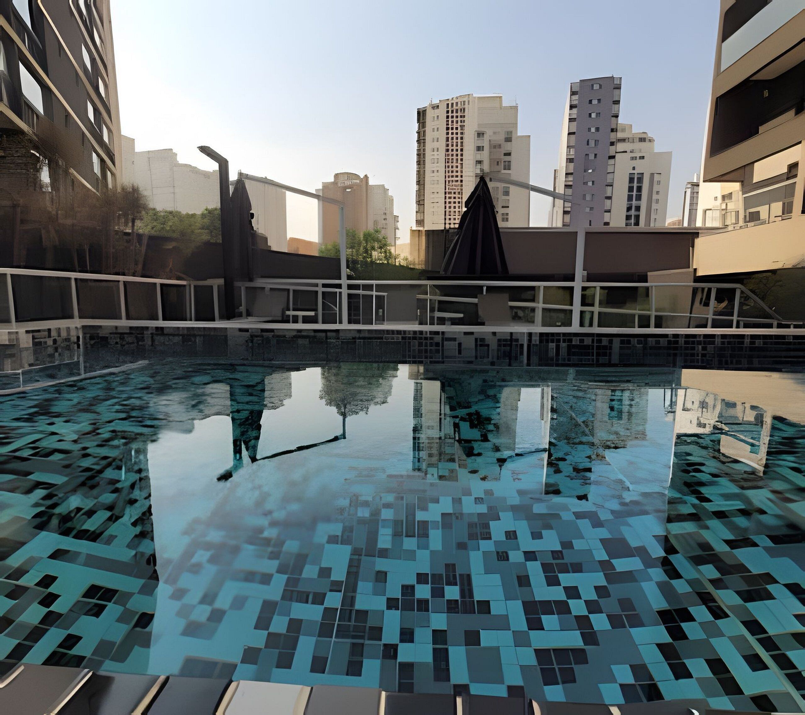 A swimming pool with a geometric tile pattern, surrounded by modern buildings and a clear sky.