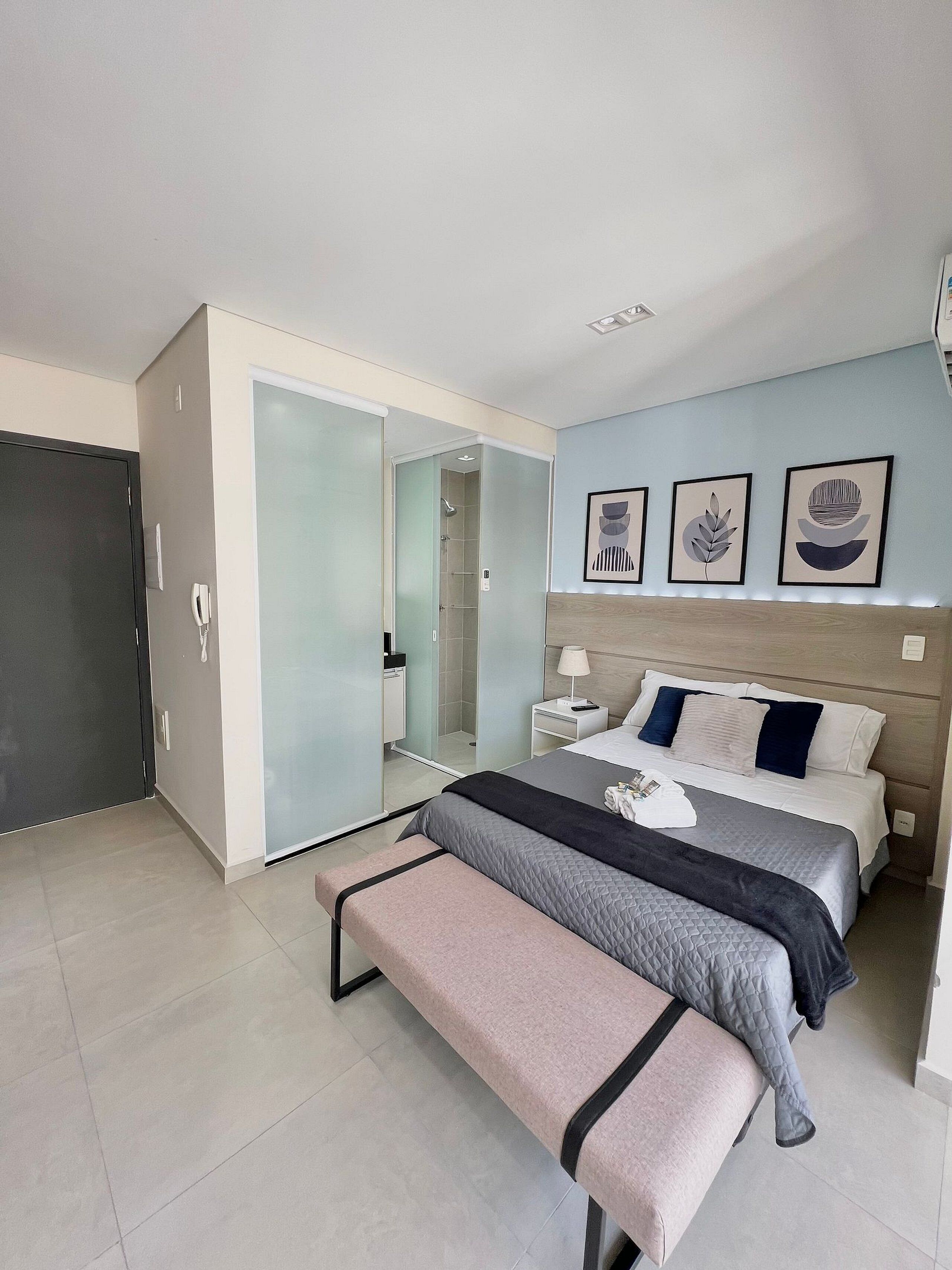 Ein modernes Schlafzimmer mit Bett, Nachttischen, einer Bank, einem begehbaren Kleiderschrank und einer Dusche.