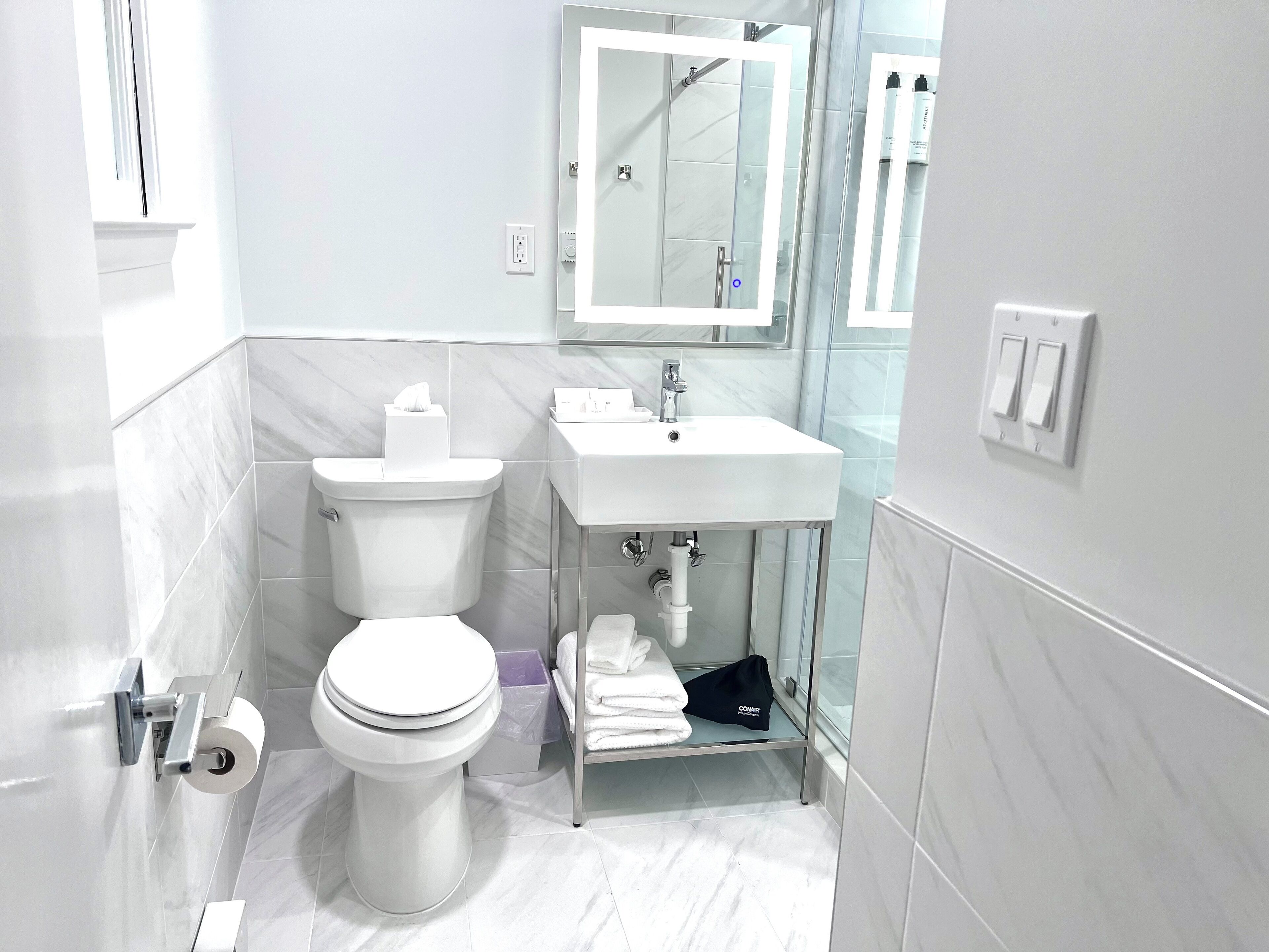 Un baño moderno con inodoro, lavamanos y cabina de ducha de vidrio.