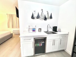 A compact kitchenette with a fridge, a sink, and a coffee maker.