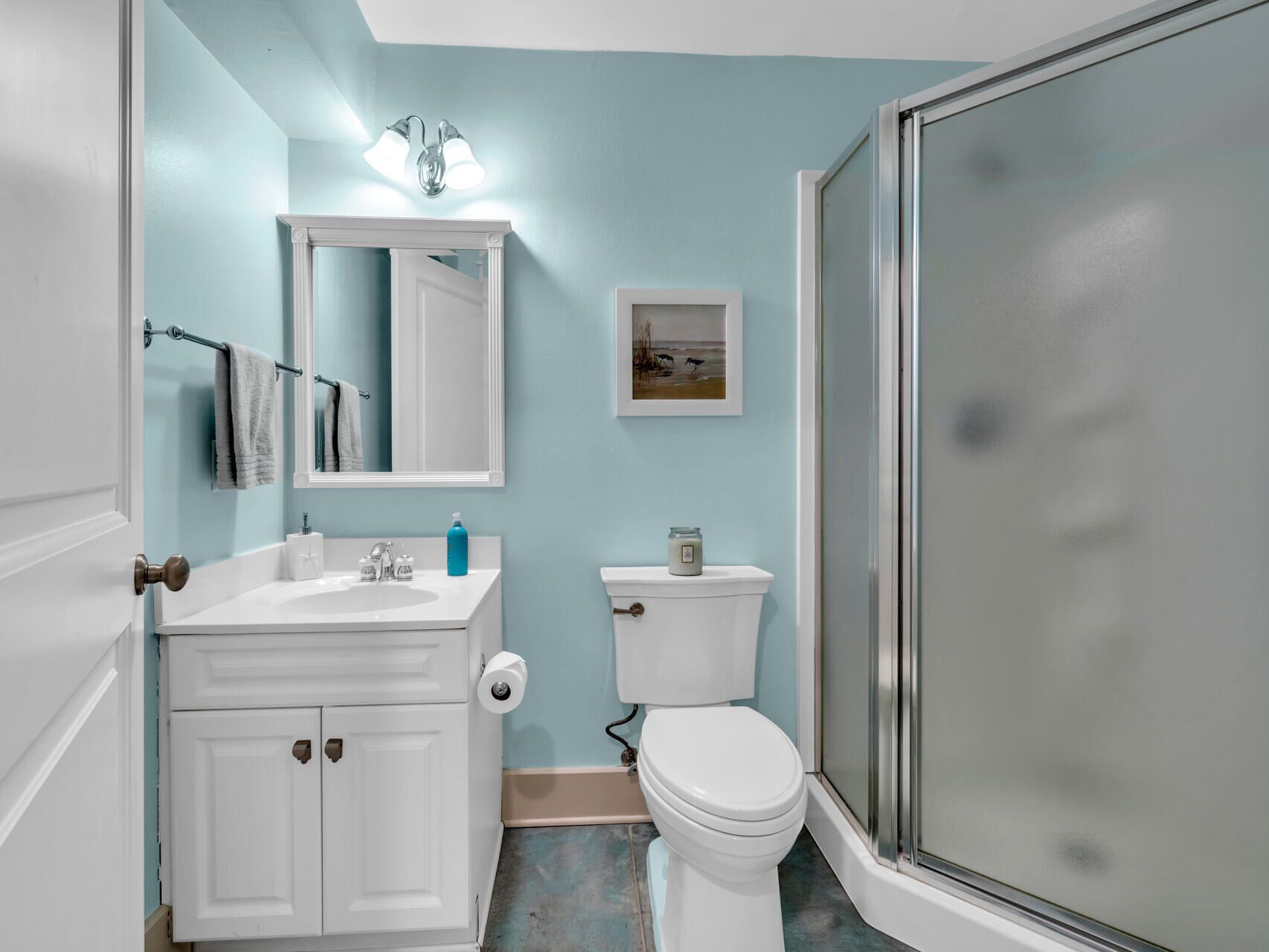A bathroom with a white vanity, a toilet, and a glass shower enclosure.