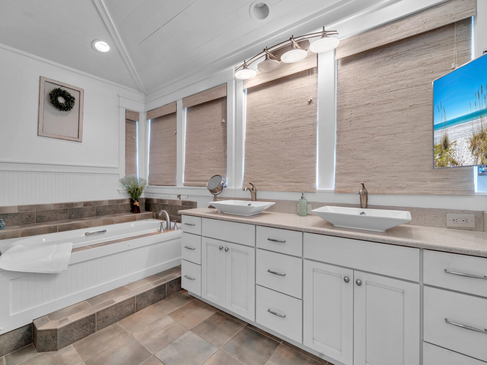 A modern bathroom with a large bathtub, two sinks, and a large mirror.