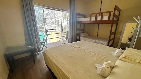 Una habitación con literas, una mesita pequeña y una ventana con cortinas.
