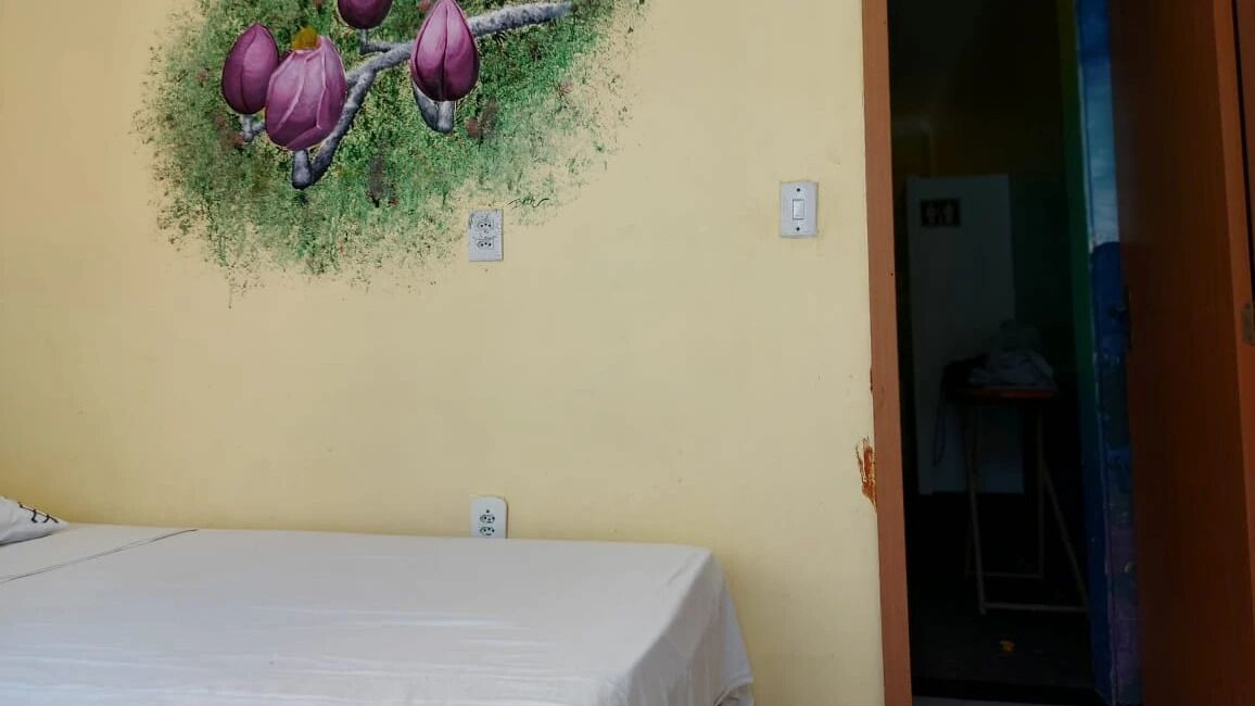 Una habitación con una cama, un enchufe en la pared y una puerta que da a otra habitación.