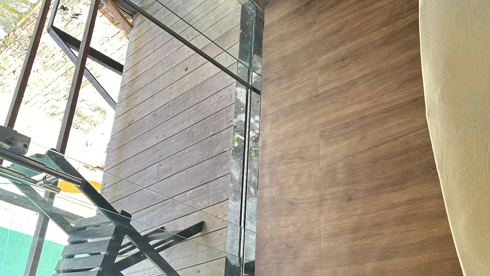 A room with a wooden floor, a metal staircase, and a large window.