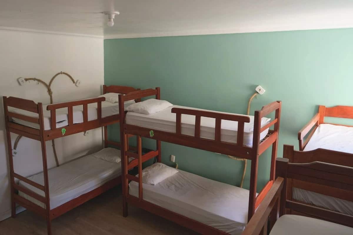 Quarto com beliches, ventoinha no teto e parede verde.