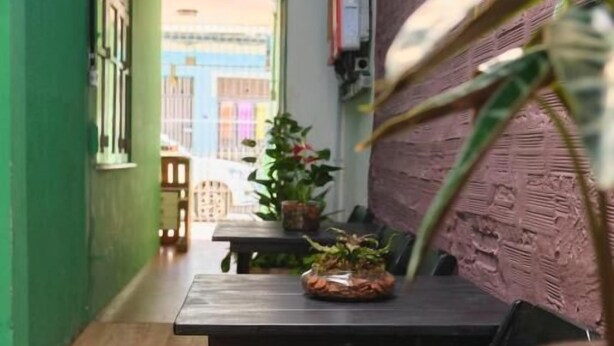Un estrecho pasillo con suelo de madera, pared verde y una mesa con sillas.