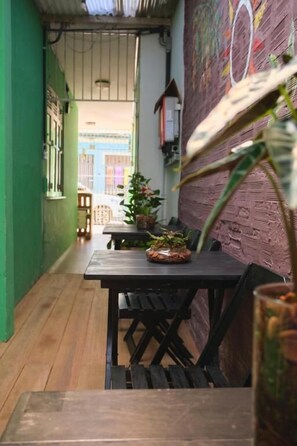 Un estrecho pasillo con suelo de madera, pared verde y una mesa con sillas.