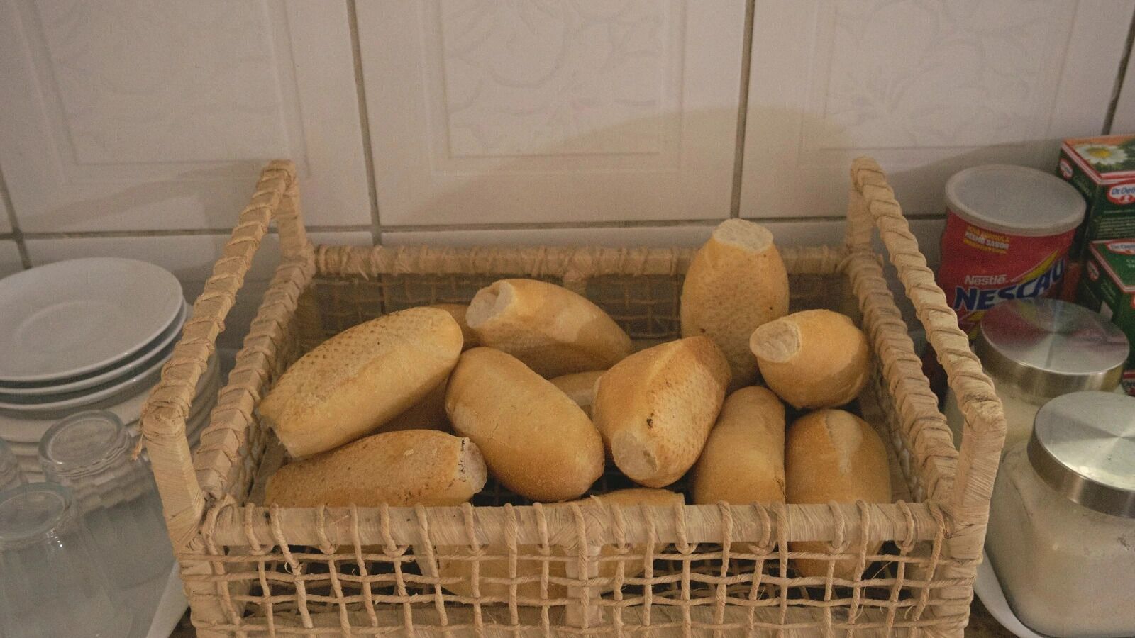 A wicker basket filled with baguettes on a kitchen counter.