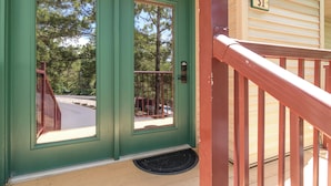 Puerta verde con una reja metálica, un letrero con el número 31 y una terraza de madera con barandilla roja.