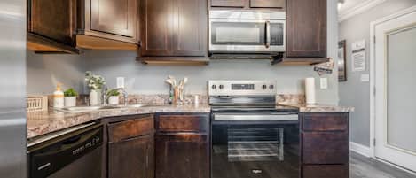 A kitchen with dark wood cabinets, stainless steel appliances, and a granite countertop.
