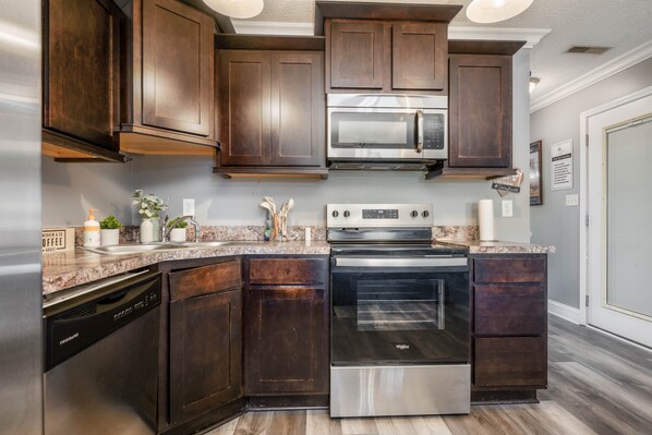 A kitchen with dark wood cabinets, stainless steel appliances, and a granite countertop.