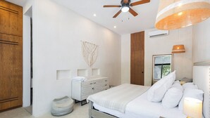 A modern bedroom with a bed, bedside lamp, and a ceiling fan. - Manor Tulum (Tulum)