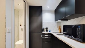 Une cuisine moderne avec des meubles de couleur sombre, un four à micro-ondes et une machine à café.
