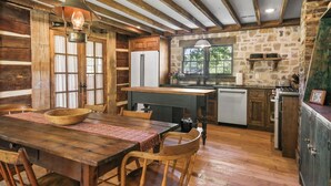 Una cocina rústica con vigas de madera, una mesa de comedor de madera y una pared de piedra.