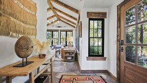 Un pasillo con techo de madera rústica, un ventanal con vistas a la vegetación y un tapiz estampado en el suelo.