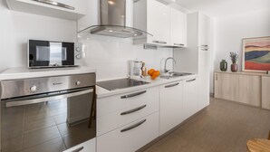 Una cucina moderna con mobili bianchi, elettrodomestici in acciaio inossidabile e piano cottura in vetro.
