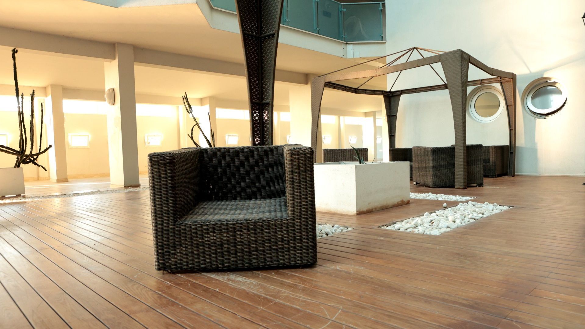 Un interior moderno con una silla de mimbre, piso de madera y una estructura geométrica.