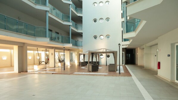 A spacious indoor atrium with a central column, multiple balconies, and a covered seating area.