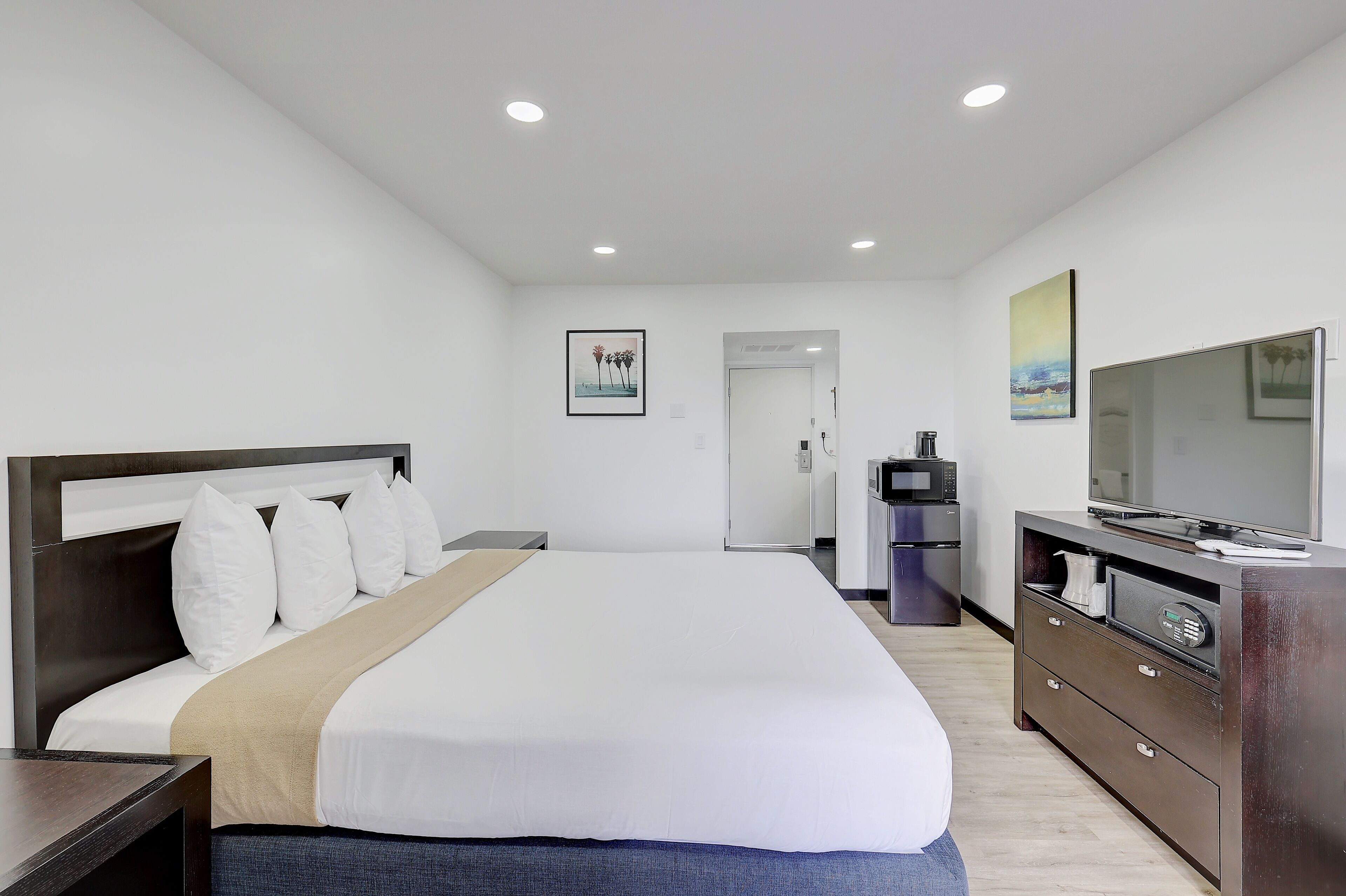 Habitación de hotel con una cama grande, un aparador, un televisor y una puerta que da a un baño.