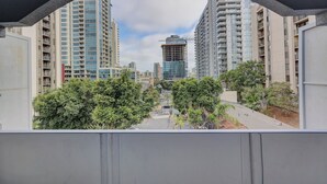 A view through an arched window of a residential area with tall buildings, trees, and a construction site in the distance. - Ash&9th (San Diego)