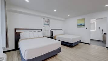 Quarto de hotel com duas camas de solteiro, uma janela grande e um banheiro visível ao fundo.