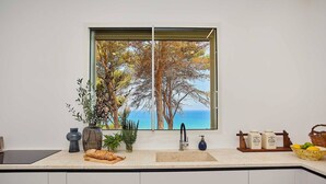 Una cocina con un ventanal grande, un lavamanos y una encimera con frascos y una cesta.