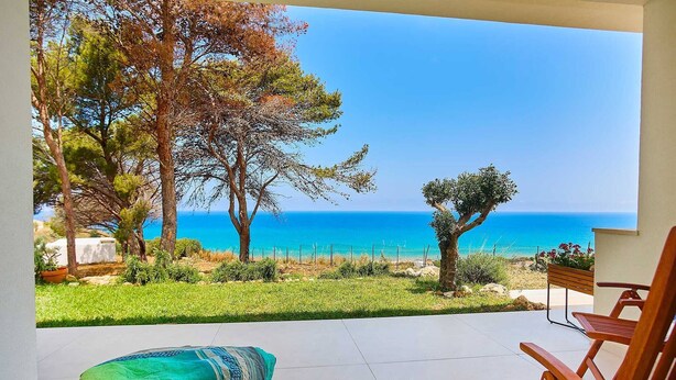 Un patio con muebles de madera y vista al mar.