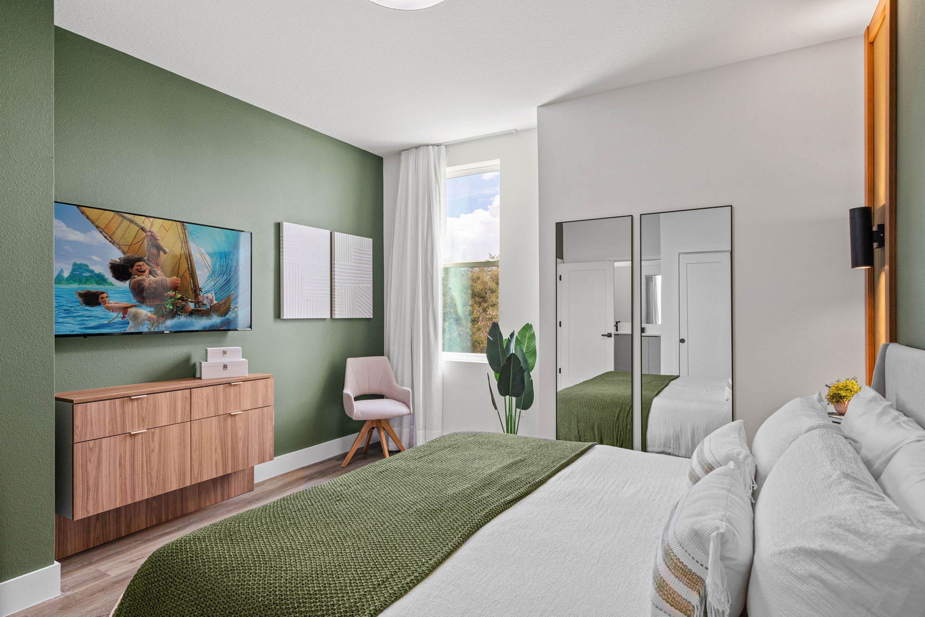 Un dormitorio con una cama, un tocador, una silla, un ventanal y un cuadro en la pared.