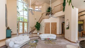 A spacious living area with a high ceiling, a staircase, and a large window. - Spacious house walking distance to the beach (Lauderdale-by-the-Sea)