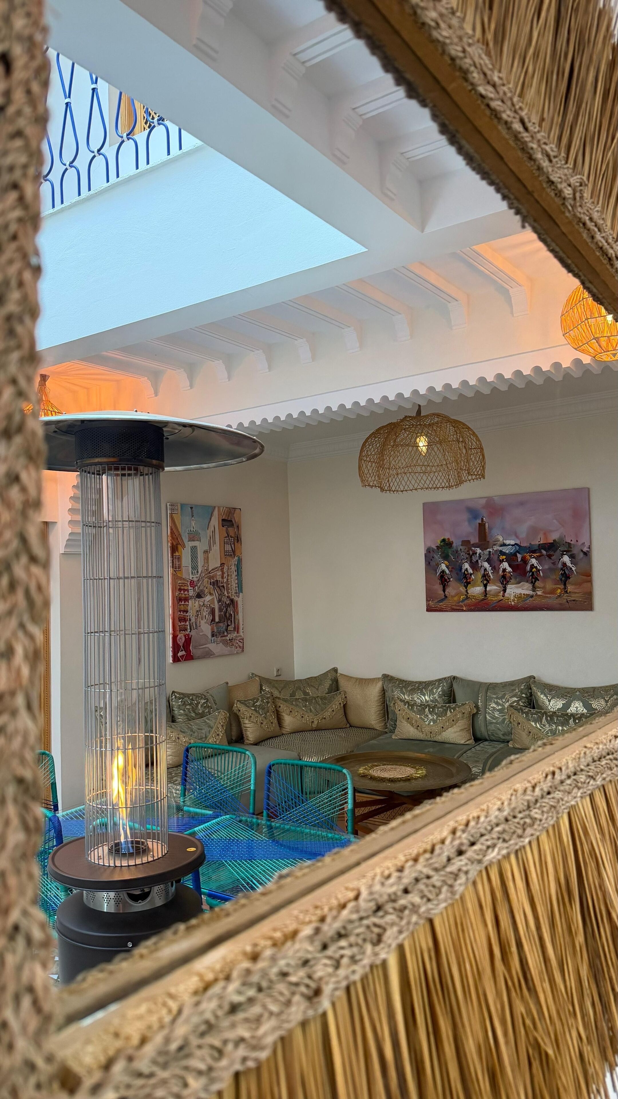 Un salon chaleureux avec un canapé, des fauteuils bleus, une lampe de sol décorative et des œuvres d’art accrochées aux murs.