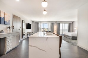 Een moderne hotelkamer met een marmeren bar, een bed, een zithoek en uitzicht op de stad.