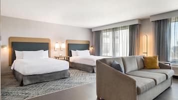 Een hotelkamer met twee bedden, een bank, een nachtkastje en een lamp.