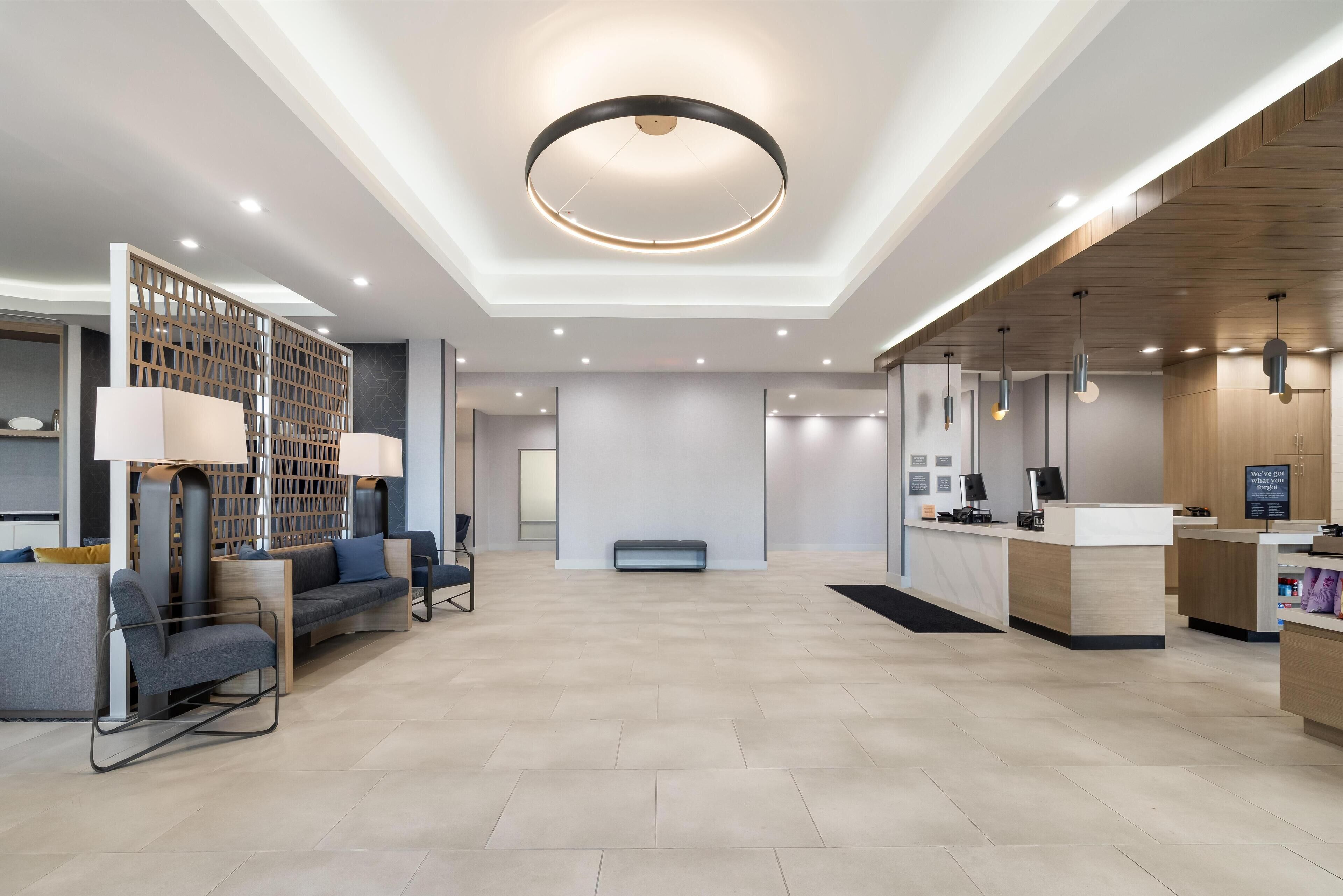 A modern hotel lobby with a reception desk, seating area, and a decorative wall.