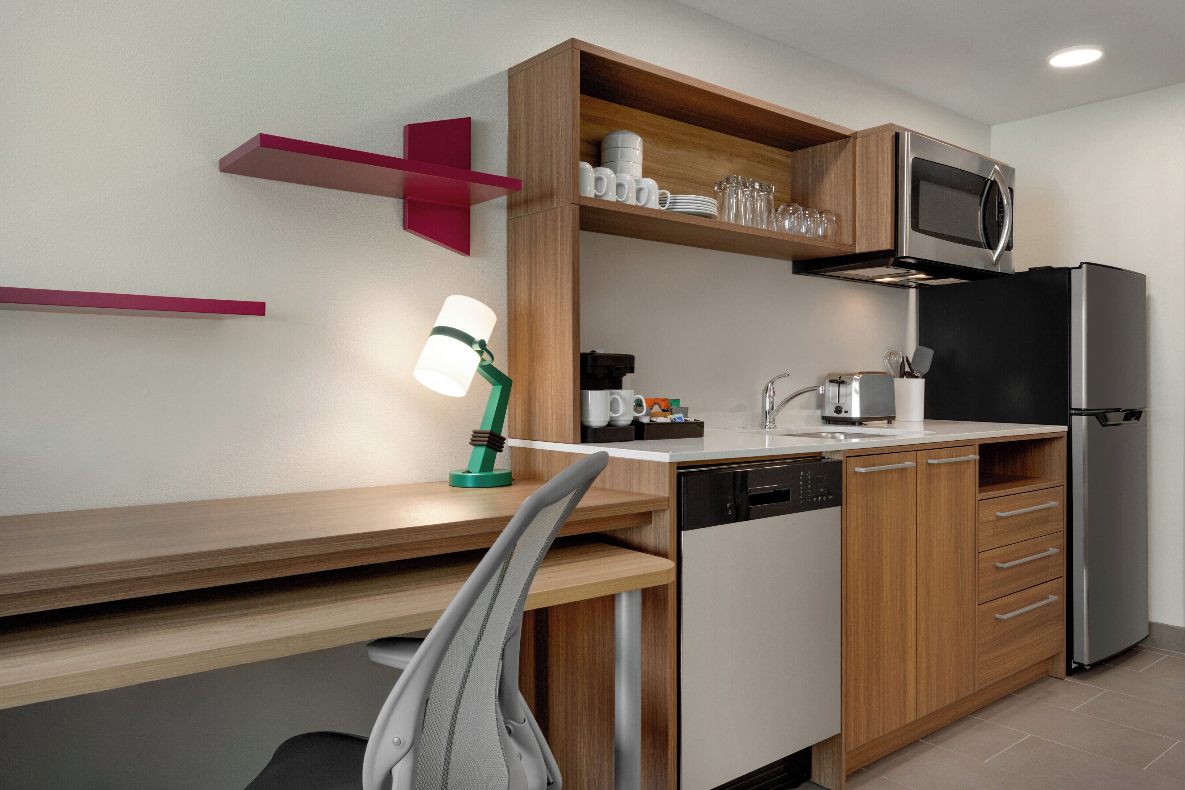 A modern kitchen with wooden cabinets, a stainless steel refrigerator, a microwave, and a dishwasher.
