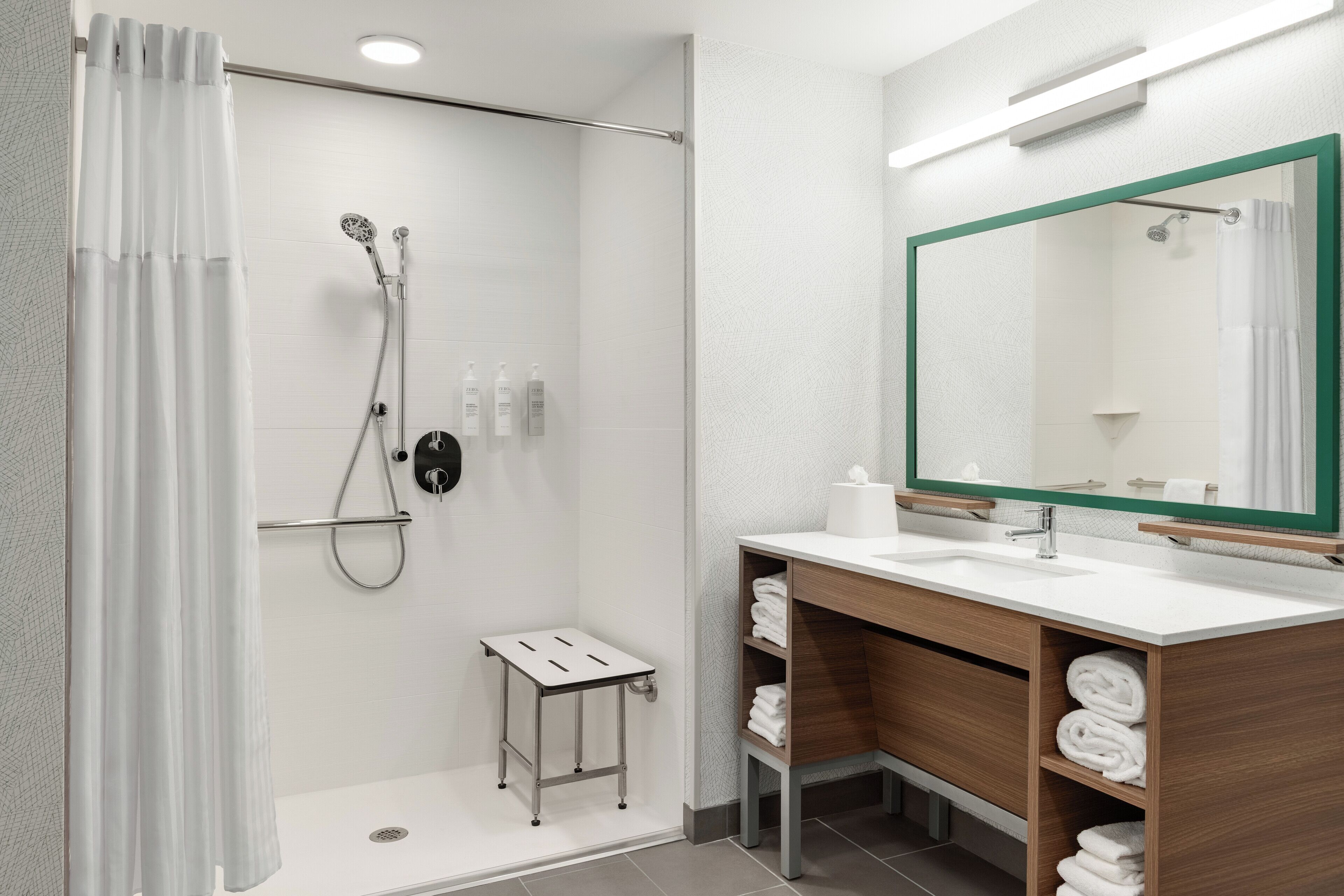 A modern bathroom with a shower, a sink, a mirror, and a small table.