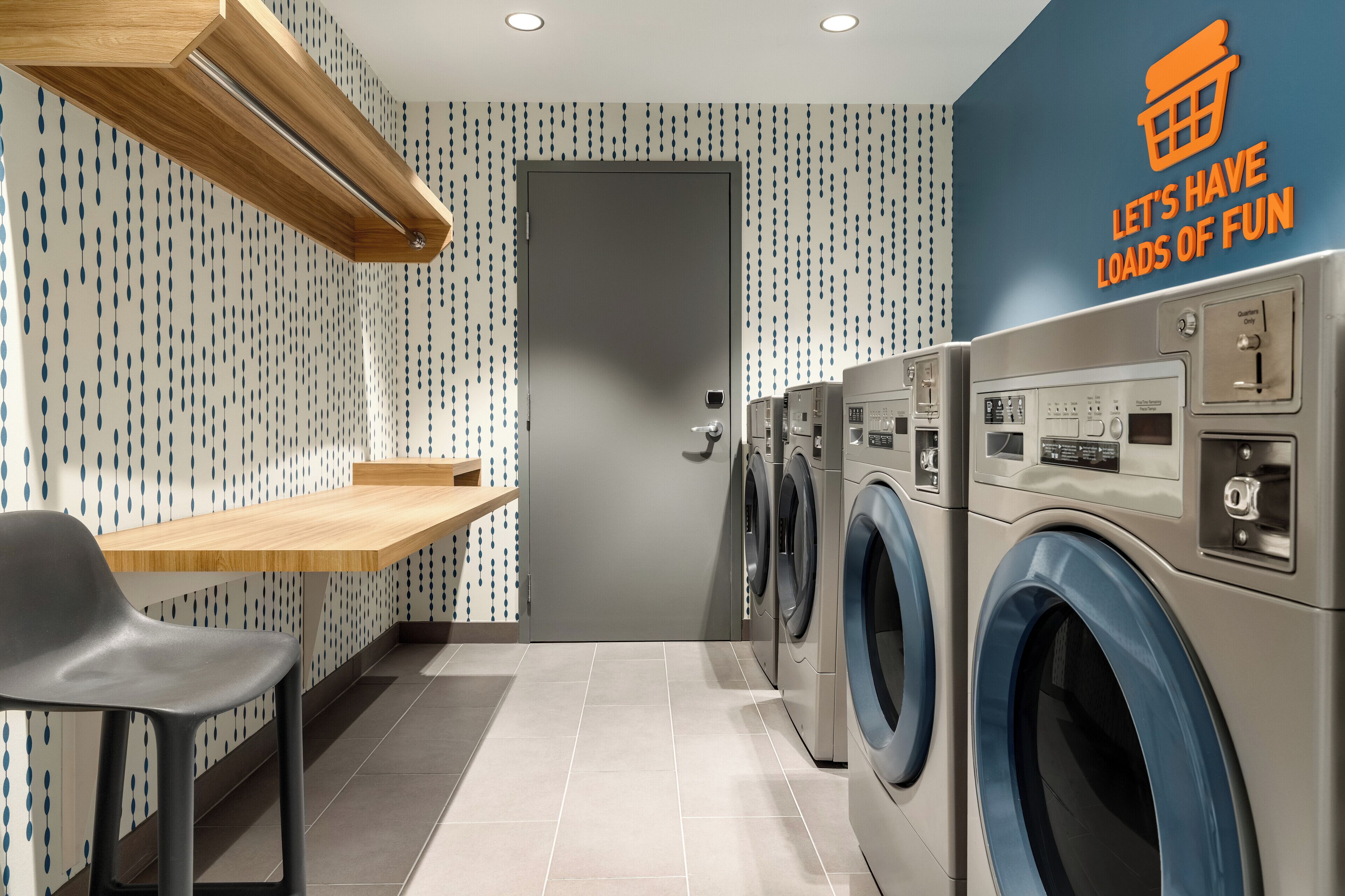 A laundry room with a washing machine, dryer, and a wooden bench.