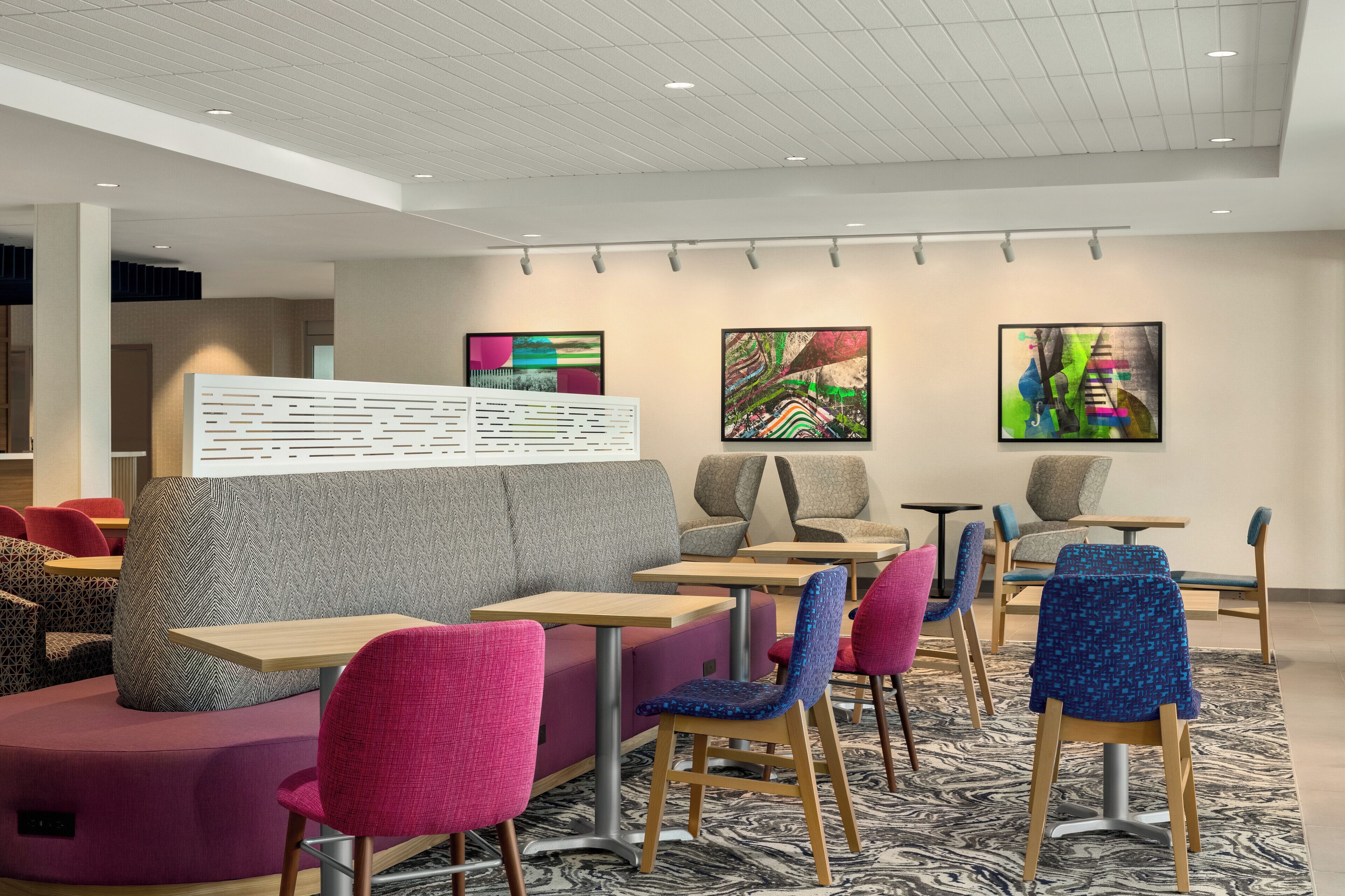 A modern restaurant with booths, tables, and colorful chairs.