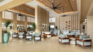 A spacious lobby with multiple seating areas, ceiling fans, and a reception desk. - Hilton Garden Inn Bali Nusa Dua (Nusa Dua)