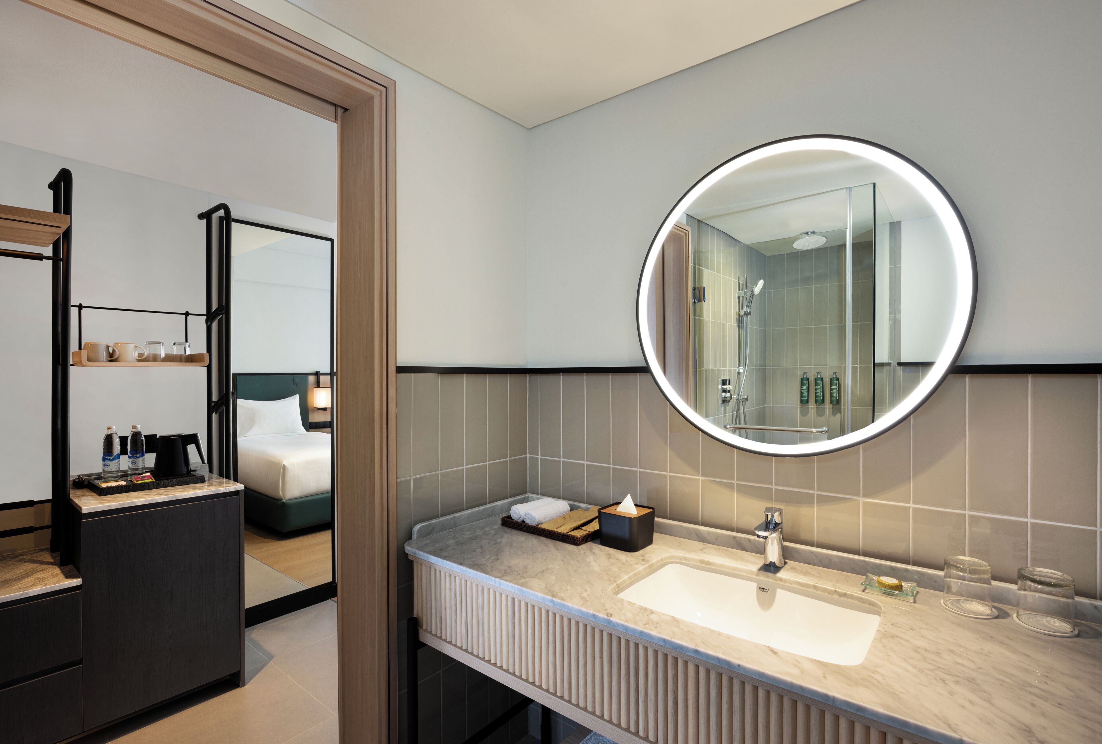A modern bathroom with a round mirror, a sink, and a shower area.