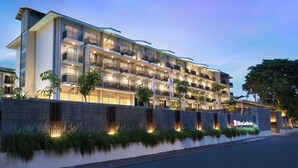 A multi-story hotel with balconies, a well-lit facade, and a landscaped front. - Hilton Garden Inn Bali Nusa Dua (Nusa Dua)
