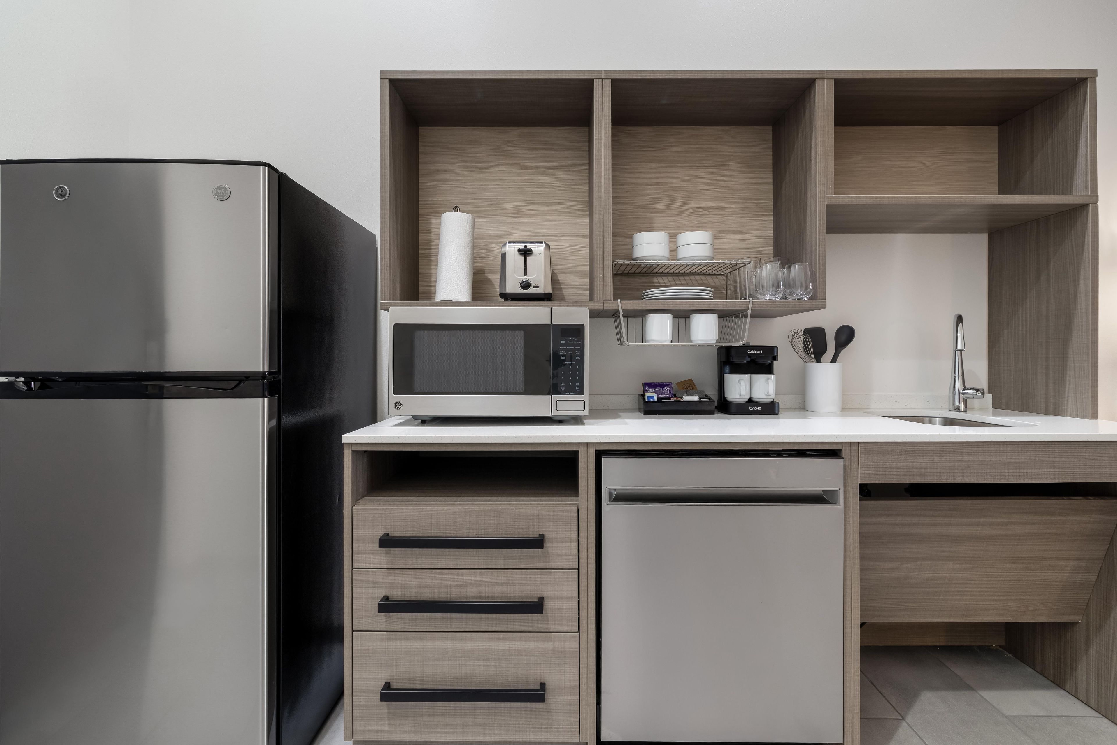 Eine moderne Küche mit einem Edelstahl-Kühlschrank, einer Mikrowelle und einer Kaffeemaschine.