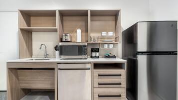 A modern kitchen with a built-in dishwasher, a stainless steel refrigerator, a microwave, and a coffee maker.