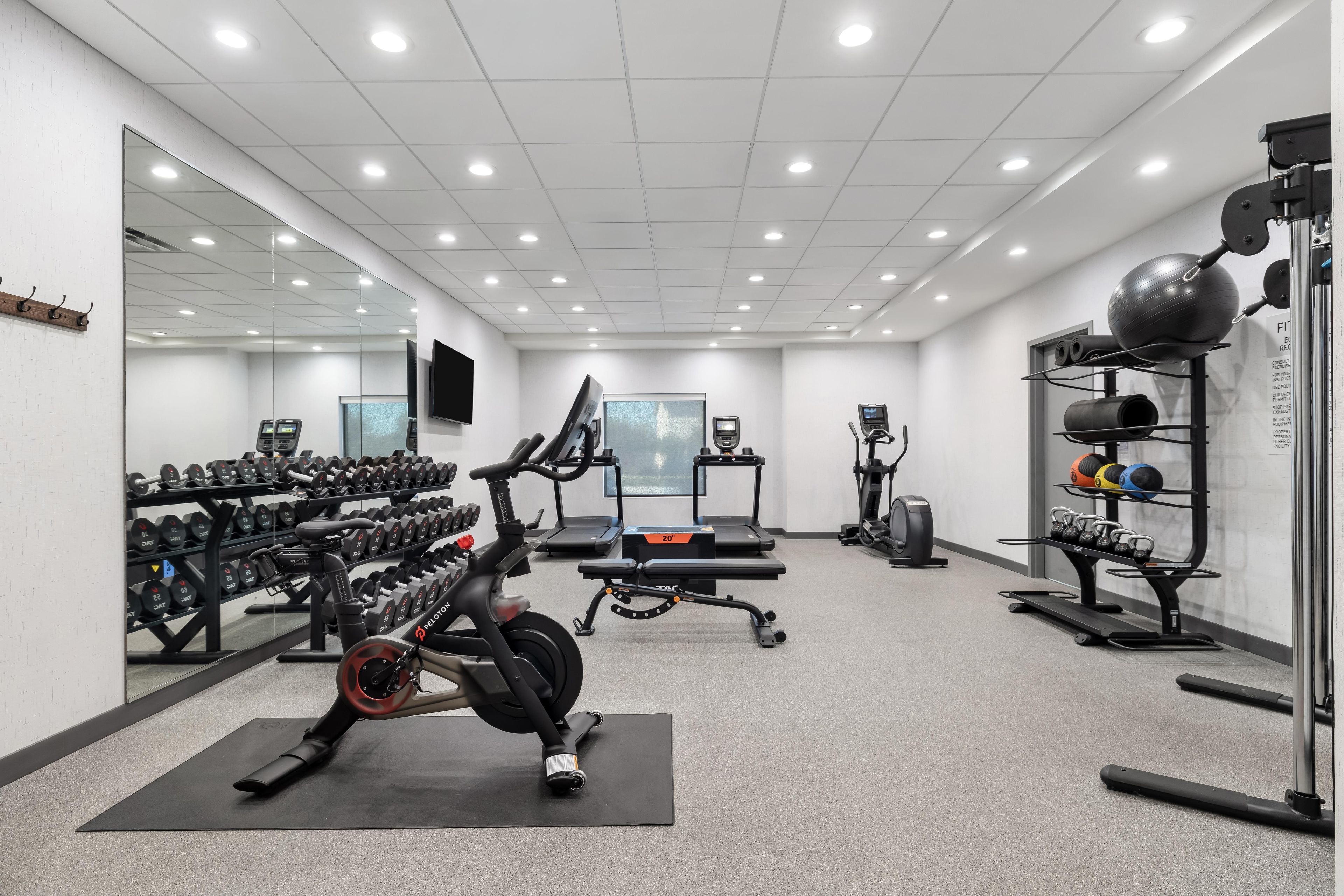 A gym with exercise equipment, a mirror, and a wall-mounted television.
