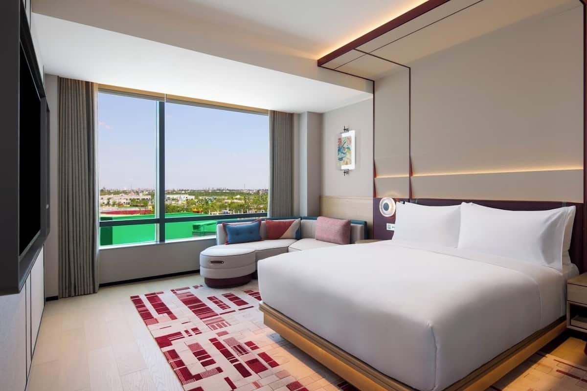 Une chambre d’hôtel moderne avec un grand lit, un canapé, une petite table et une vue sur la ville.