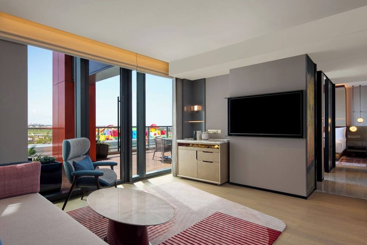 Une chambre d’hôtel moderne dotée d’un grand balcon, d’une télévision à écran plat et d’un coin salon confortable.